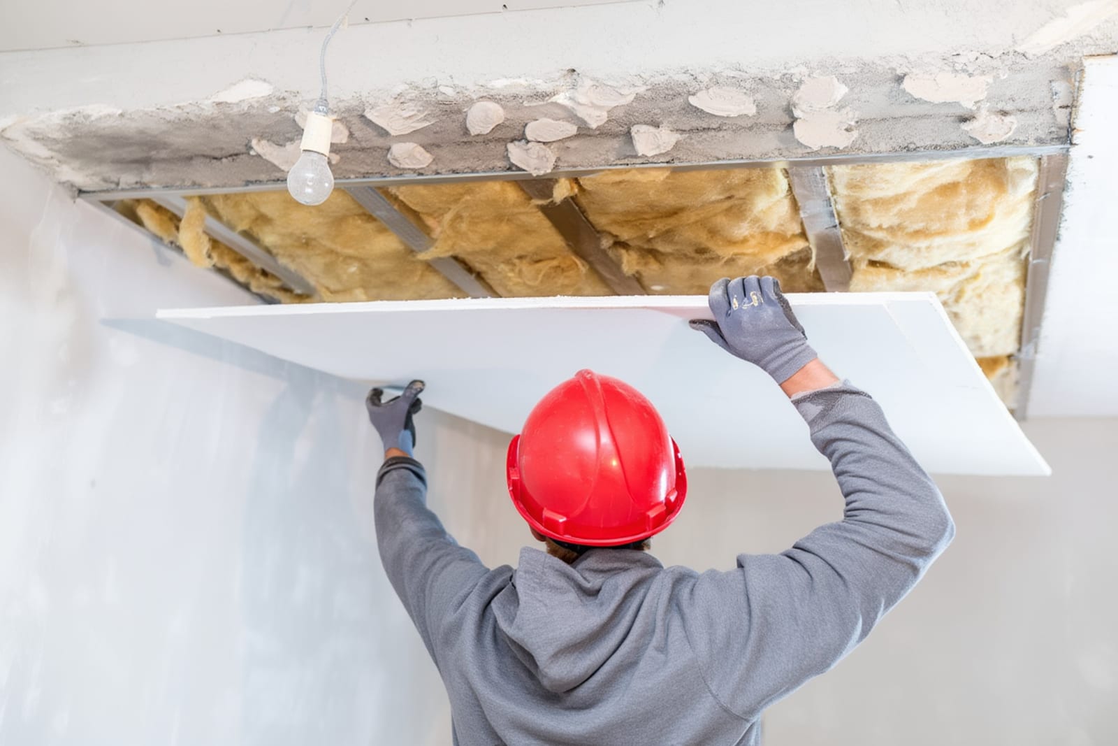 Restoration technician using moisture meter to inspect ceiling water damage during assessment